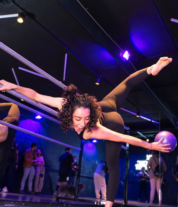 Athlete in a focused yoga warrior pose in a dark studio.