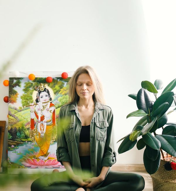 Calm person meditating in a bright, airy room with plants.