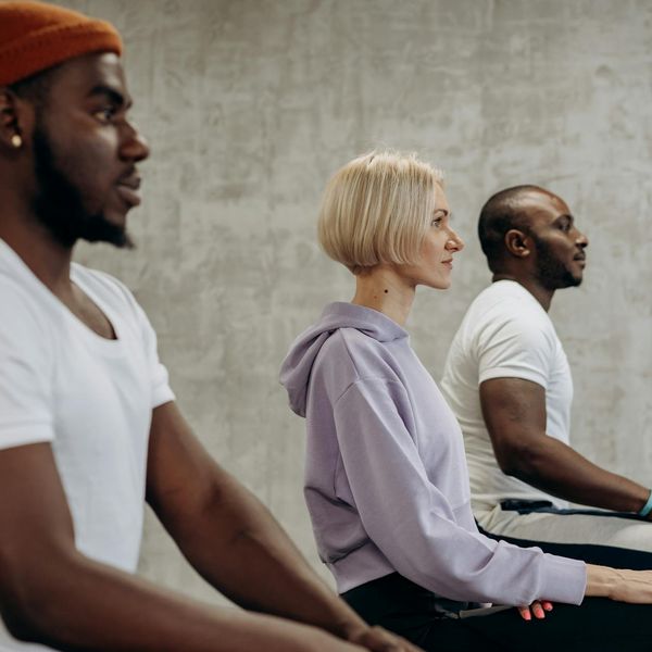 Group of athletes stretching on yoga mats in a modern gym.